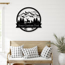 A novelty outdoor monogram sign featuring a stylized deer and mountains, with the option for a custom text or name, mounted on a wooden wall bracket.